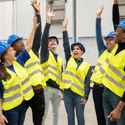 Group of happy workers celebrating success in a manufacturing environment