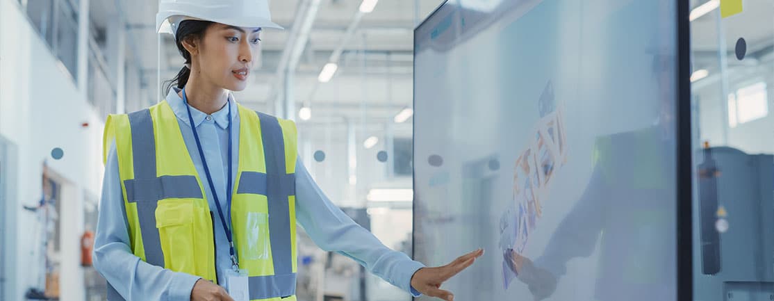 Female factory worker in a team meeting referring to a digital screen